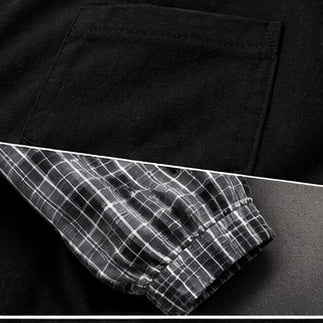 Close-up of a black garment showing a pocket and a folded cuff with a black-and-white plaid lining.